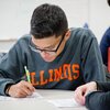 A female teaching assistant helps a male undergraduate student with an assignment during class.