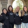 college women in matching black sweatshirts in an academic hall